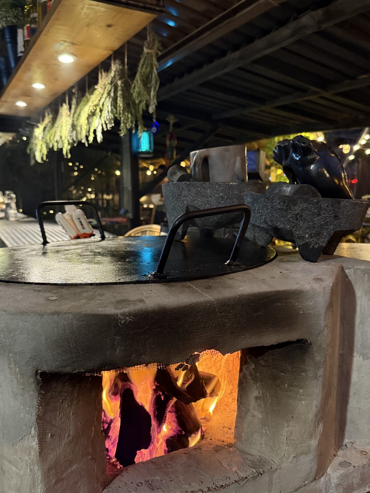 The wood-fired comal resting over glowing embers at Cebollajo